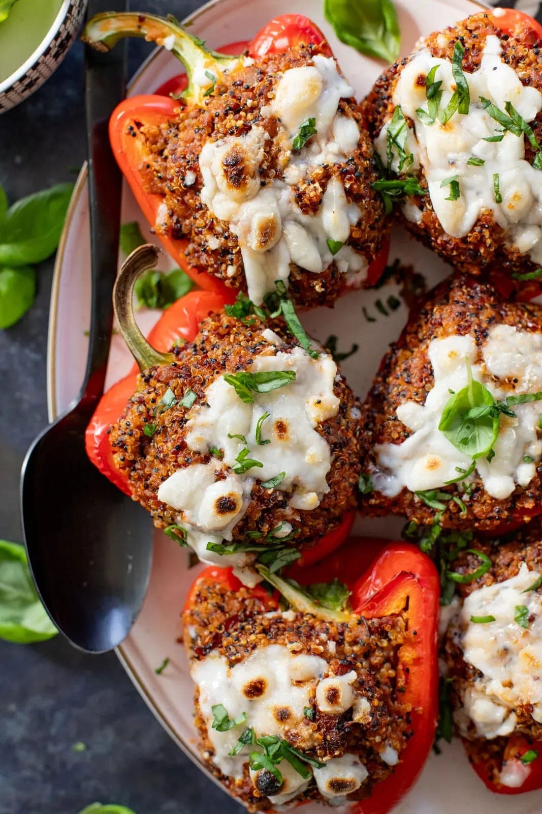 Bell peppers stuffed with quinoa and chickpeas, roasted in a baking dish.