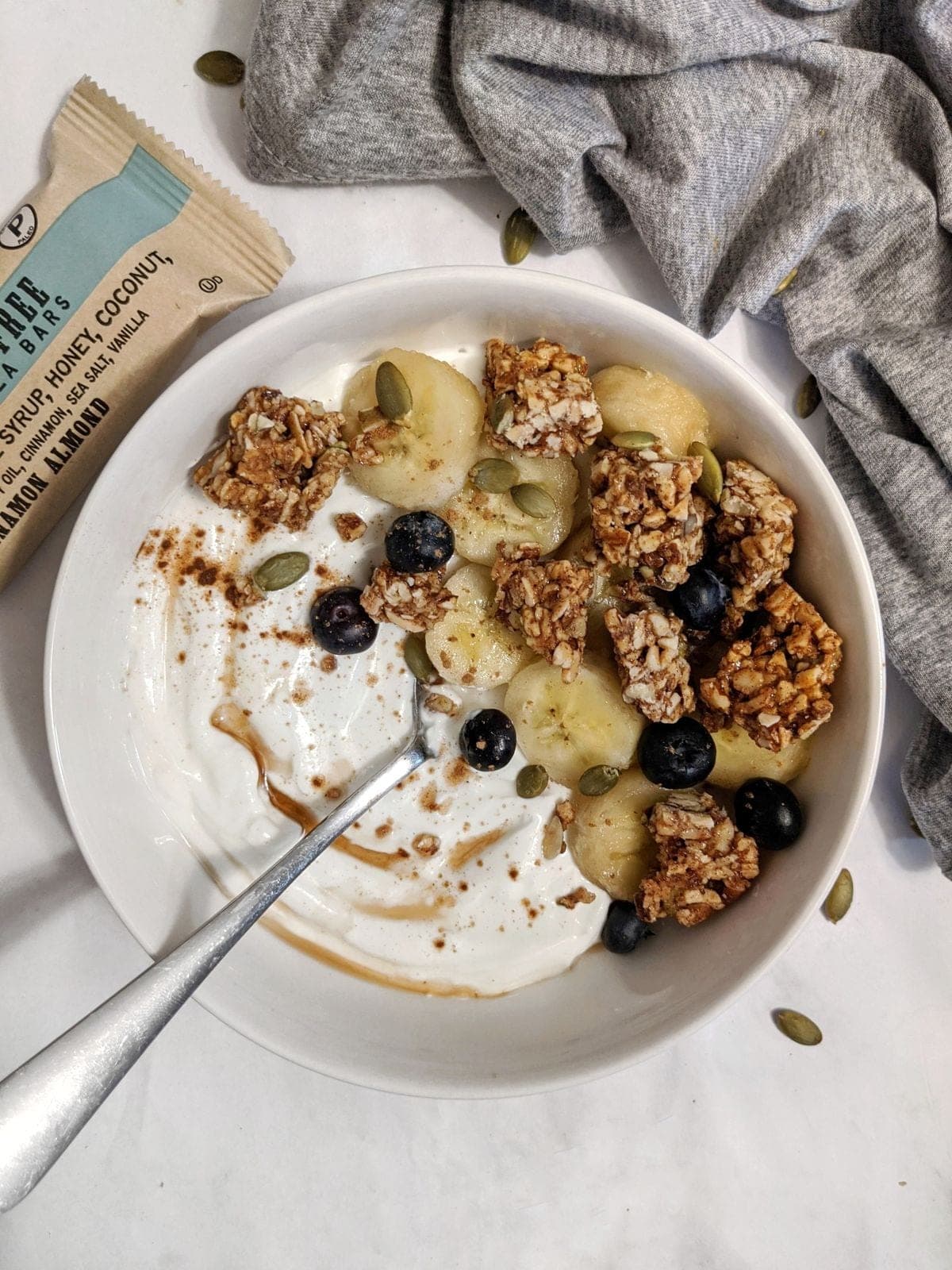 A bowl of Greek yogurt topped with berries, walnuts, and a drizzle of honey.